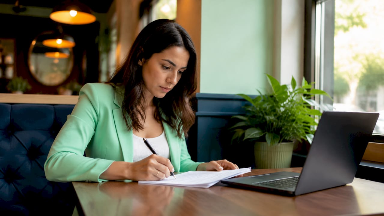 Una mujer analiza una lista de posibles clientes poco interesados en su escritorio, dentro de una oficina moderna.