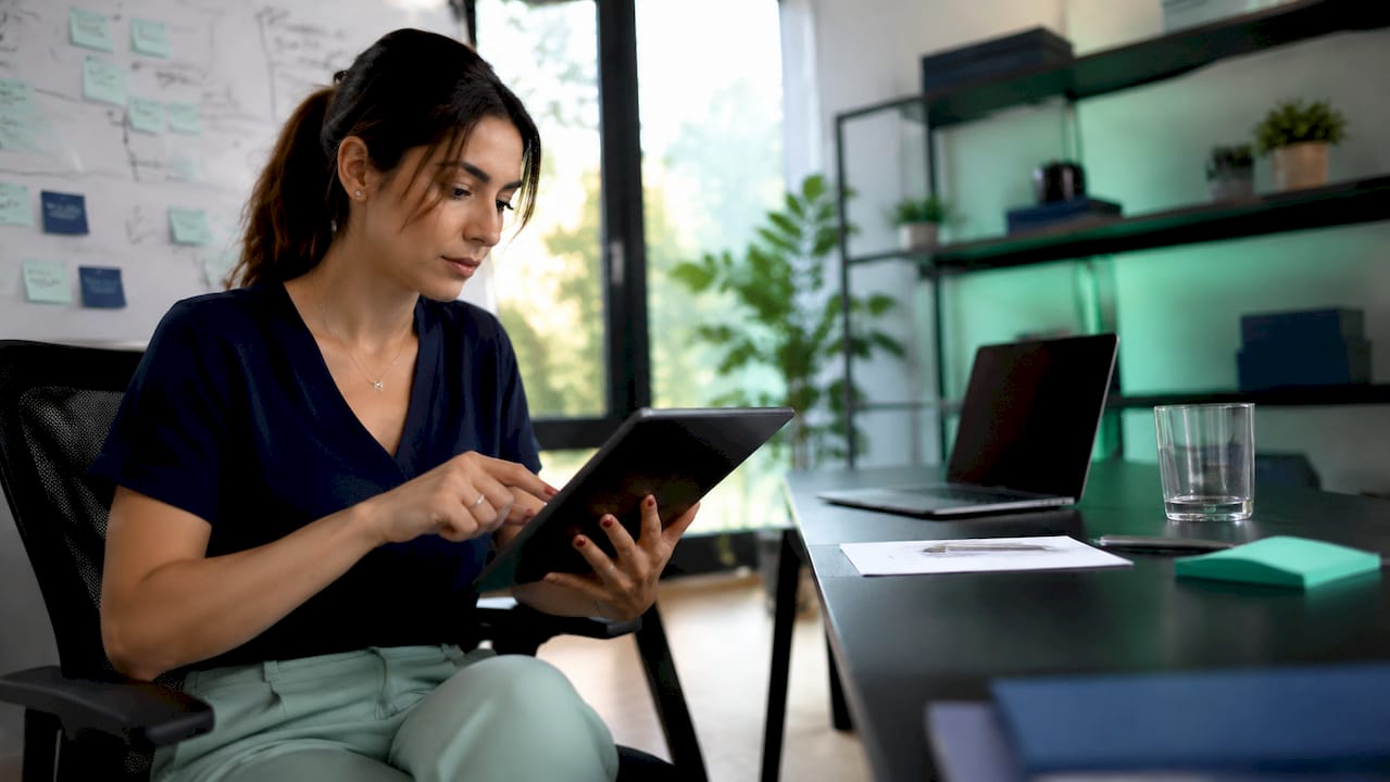 Especialista en marketing digital revisando estrategias para reducir costes desde su tablet.